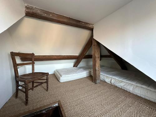 Cette chambre mansardée comprend une chaise et un lit. dans l'établissement La maison bleue, à Villerville