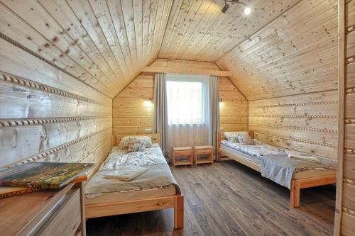 a bedroom with two beds in a wooden cabin at Gospodarstwo Agroturystyczne Bieszczadzki Bliźniak in Baligród