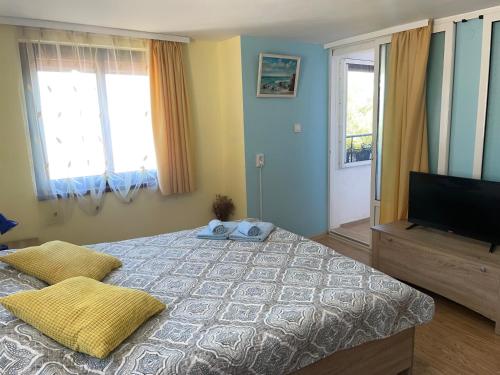 a bedroom with a bed and a flat screen tv at Къща за гости ЕЛЕНИ in Sozopol
