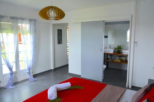 a bedroom with a red bed and a bathroom at Villa Anj'any DESHAIES - 5 minutes à pieds de la plage in Deshaies