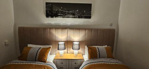 a bedroom with two beds and two lamps on a table at Glebe House - 2 Bedroom Luxury House with 4 Beds, Free Private Parking with Access to City Centre, and Near the Motorway in Moston