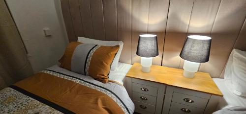 a bedroom with a bed and two lamps on a nightstand at Glebe House - 2 Bedroom Luxury House with 4 Beds, Free Private Parking with Access to City Centre, and Near the Motorway in Moston