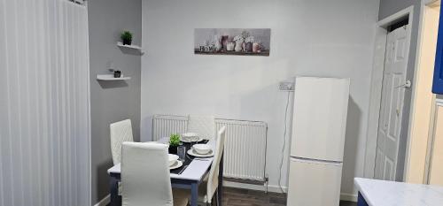 a kitchen with a table and chairs and a refrigerator at Glebe House - 2 Bedroom Luxury House with 4 Beds, Free Private Parking with Access to City Centre, and Near the Motorway in Moston