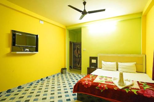a yellow room with a bed and a ceiling fan at Sea Smile Inn in Mandarmoni