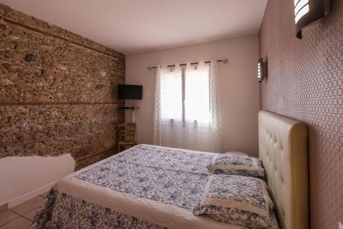 une chambre avec un lit et un mur de briques dans l'établissement Maison Bompas 6 personnes piscine et jacuzzi, à Bompas