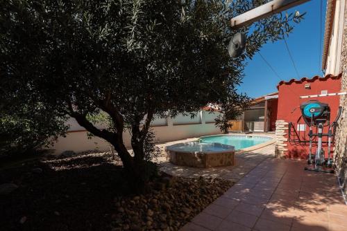 - une piscine avec un arbre à côté d'un bâtiment dans l'établissement Maison Bompas 6 personnes piscine et jacuzzi, à Bompas