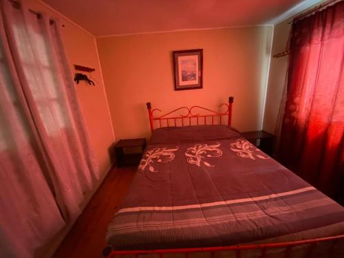 a small bedroom with a bed with red curtains at Cabaña Las Cruces, a pasos de la playa in Las Cruces