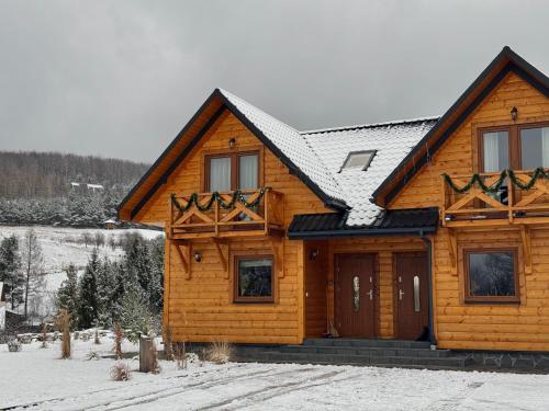 a log cabin in the snow with at Gospodarstwo Agroturystyczne Bieszczadzki Bliźniak in Baligród
