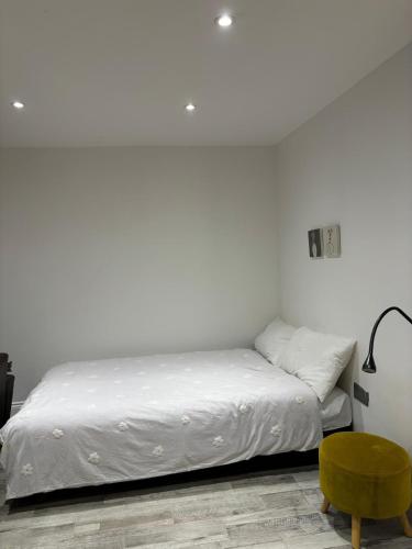 a white bedroom with a bed and a green chair at Hendon Basement Studio in Hendon