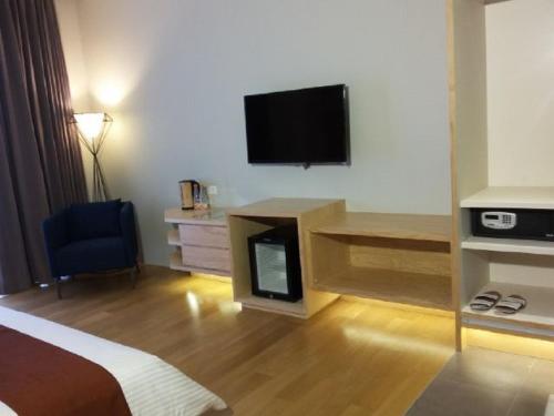 a hotel room with a bed and a tv on the wall at Tama Boutique Hotel in Bandung