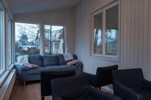 a living room with a blue couch and windows at Danderyd - Eget hus med 12 min till STHLM city in Danderyd