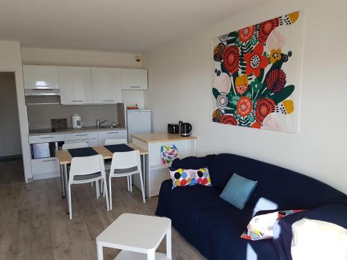 un salon avec un canapé bleu et une cuisine dans l'établissement Grand T2, 4 personnes, Clim, Parking, Proche centre, à Sanary-sur-Mer