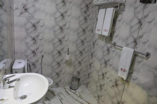 a bathroom with a white sink and marble walls at Appart-Hôtel BEL ANFA in Casablanca