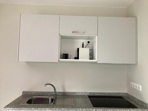 une cuisine avec des armoires blanches et un évier dans l'établissement F2 Ti amo 1 chambre, à Saint-Germain-lès-Corbeil