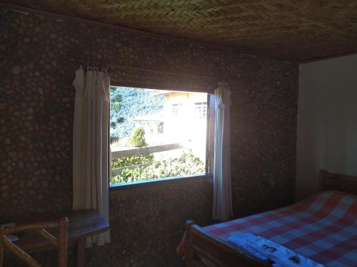 a bedroom with a window with a bed and a table at Pousada Pé da Mata in Aiuruoca