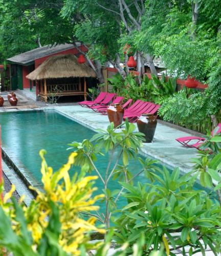 a swimming pool with pink chairs and a hut at PinkCoco Gili Trawangan - Constant Surprises - for Cool Adults Only in Gili Trawangan