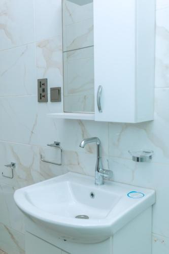 a bathroom with a white sink and a mirror at Urban Elite Stay in North Legon