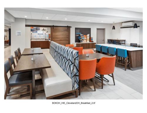 a restaurant with wooden tables and orange chairs at Holiday Inn Express Cleveland Airport - Brook Park by IHG in Brook Park
