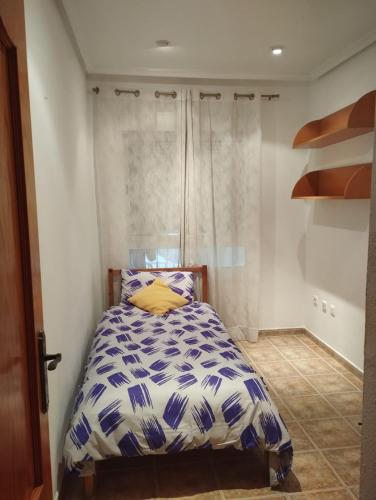 a bedroom with a bed with a blue and white comforter at Torrevieja Centro in Torrevieja