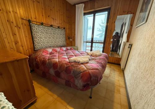 Un dormitorio con una cama grande en una pared de madera. en PALAGHIACCIO - 6 posti letto affianco al palaghiaccio di Roccaraso, en Roccaraso