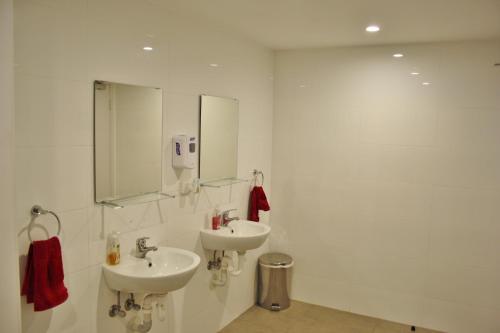 a white bathroom with two sinks and a mirror at Quokka Backpackers Hostel Perth - note - Valid passport required to check in in Perth