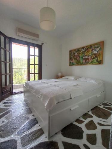 a bedroom with a large white bed with a large window at Casavita 1 in Polychrono