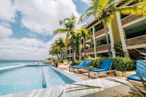 un complexe avec piscine et palmiers dans l'établissement The Bellafonte - Luxury Oceanfront Hotel, à Kralendijk