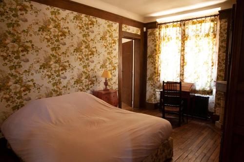 a bedroom with a bed and floral wallpaper at Chambres d'Hôtes Manoir de Beaumarchais in Les Chapelles-Bourbon