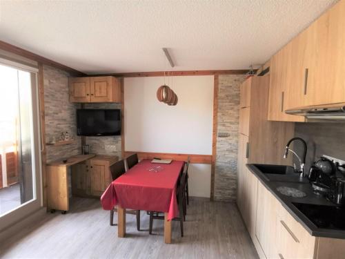 une petite cuisine avec une table et un chiffon rouge dans l'établissement Grand T2 résidence avec piscine sauna, à Huez