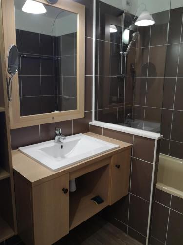 une salle de bain avec un lavabo, un miroir et une baignoire dans l'établissement Grand T2 résidence avec piscine sauna, à Huez