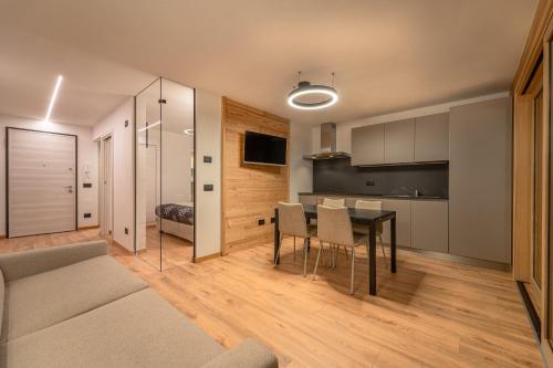 a living room with a table and a kitchen at Appartamenti Ai Due Campanili in Pellizzano
