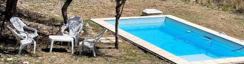 Dos sillas y una piscina en un patio. en Terra Bella PB2, en San Antonio de Arredondo
