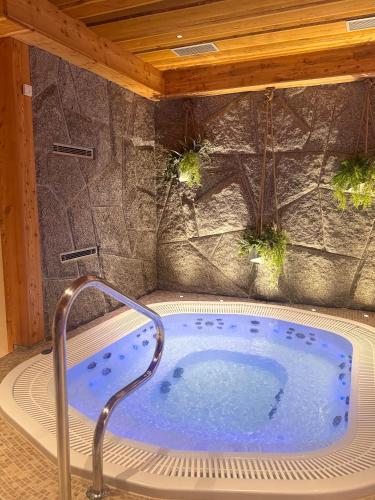 a jacuzzi tub in a room with a stone wall at Wellness Penzion Zora Family in Tatranská Lomnica