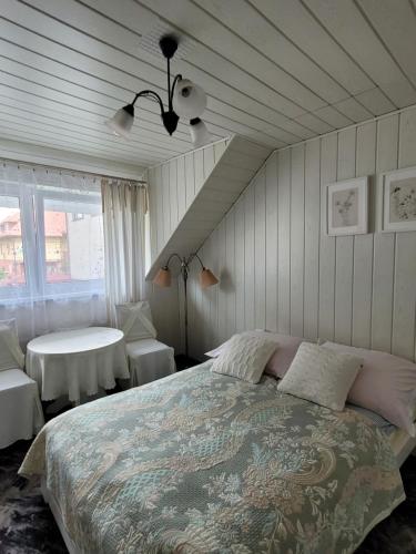 a bedroom with a large bed and a table at Pokoje Klif in Łeba