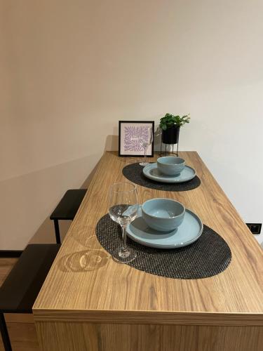 a wooden table with two plates and wine glasses at Apartament Piłsudskiego in Tychy