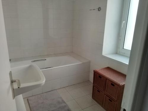 La salle de bains blanche est pourvue d'un lavabo et d'une baignoire. dans l'établissement L ancre marine, à Penmarcʼh