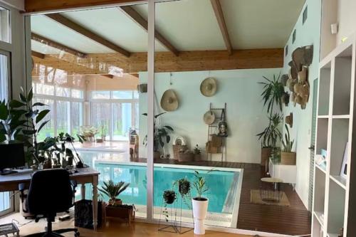 a large room with a swimming pool with potted plants at Villa Verde - piscine intérieure proche Zoo de Beauval et Châteaux de la Loire in Gièvres