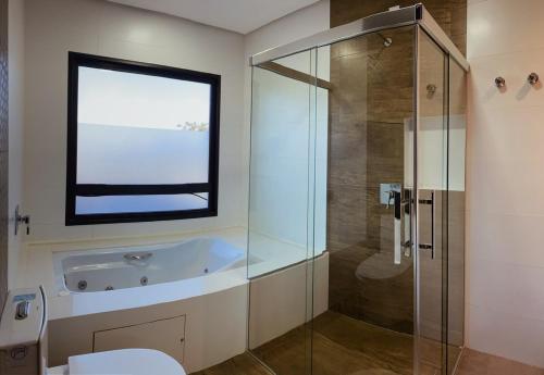 ein Badezimmer mit Badewanne und Glasdusche in der Unterkunft Casa 4 Suites Garopaba, Rosa Internacional - Surfland in Garopaba
