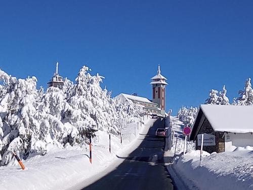a road covered in snow with a building and trees at Ferienwohnung Sonnenleithe Urlaub im Denkmal in Breitenbrunn