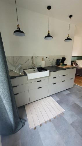 La cuisine est équipée de placards blancs, d'un évier et de lampes suspendues. dans l'établissement Parenthèse en Terre Breizh, à Bohal