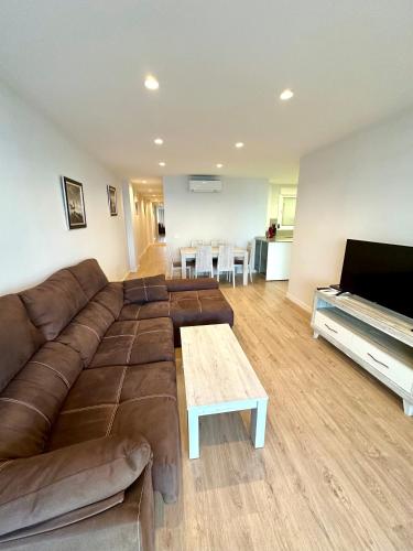 a living room with a brown couch and a television at Horizonte 3 Charming apartment with breathtaking sea view at first line of Fuengirola beach in Fuengirola