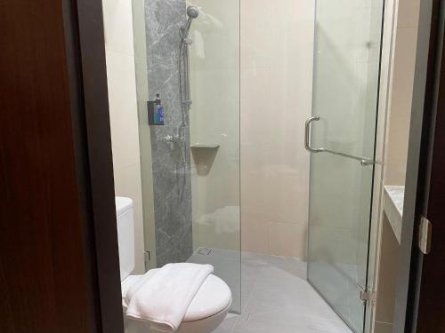 a bathroom with a toilet and a glass shower at Hexton Hotel Lampung by Amazing in Bandar Lampung