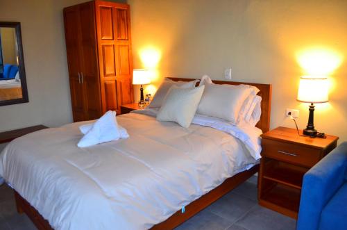 a bedroom with a large white bed with two lamps at Monteverde Best Inn - HOTEL in Tenza