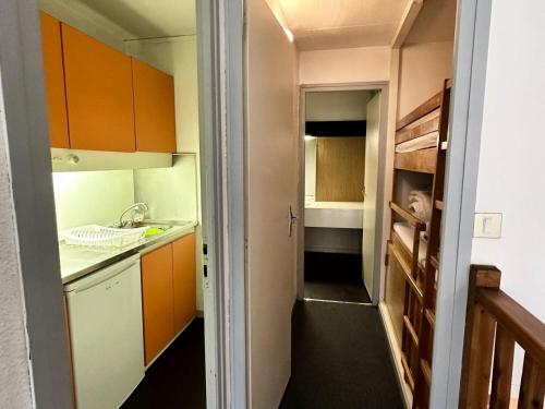 une petite cuisine avec des armoires orange et un évier dans l'établissement Résidence Le Tourmalet - maeva Home - Studio 4 personnes - Confort MAE-0401, à La Mongie