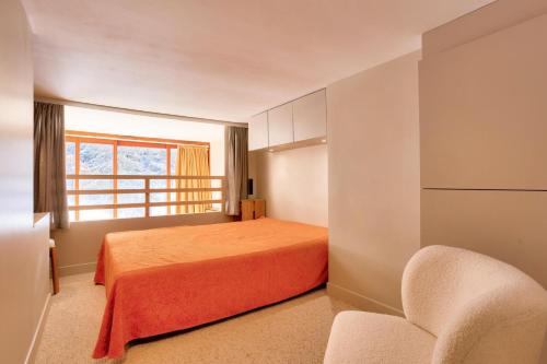 une chambre avec un lit, une fenêtre et une chaise dans l'établissement Résidences quartier Charmettoger - maeva Home - Appartement avec balcon vue montagne 2 pièces 4 personnes - Prestige - super Home MAE-3511, à Arc 1800