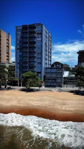 a beach with a tall building in the background at Pé na areia incrível in Piçarras
