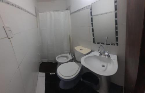 Un baño blanco con inodoro y lavabo. en Cabañas cochico, en Villa Carlos Paz