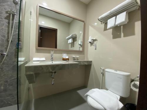 a bathroom with a toilet and a sink and a mirror at Hexton Hotel Lampung by Amazing in Bandar Lampung
