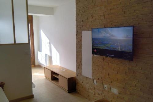 un salon avec une télévision sur un mur en briques dans l'établissement Nice T2 with south facing terrace Flumet, à Flumet