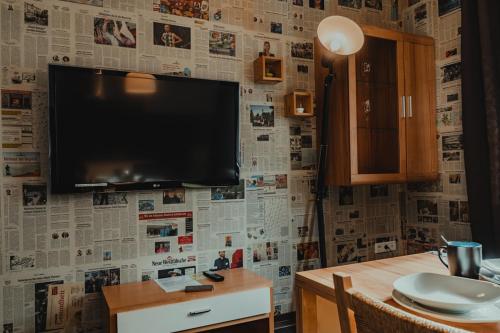a living room with a tv on a wall with newspapers at HeinrichsOase 13 - Bielefeld Mitte in Bielefeld